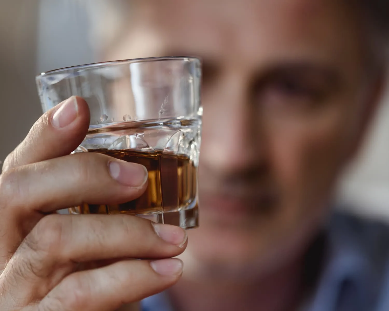 Sløret mand ser på glas med drink Sløret mand ser på glas med drink